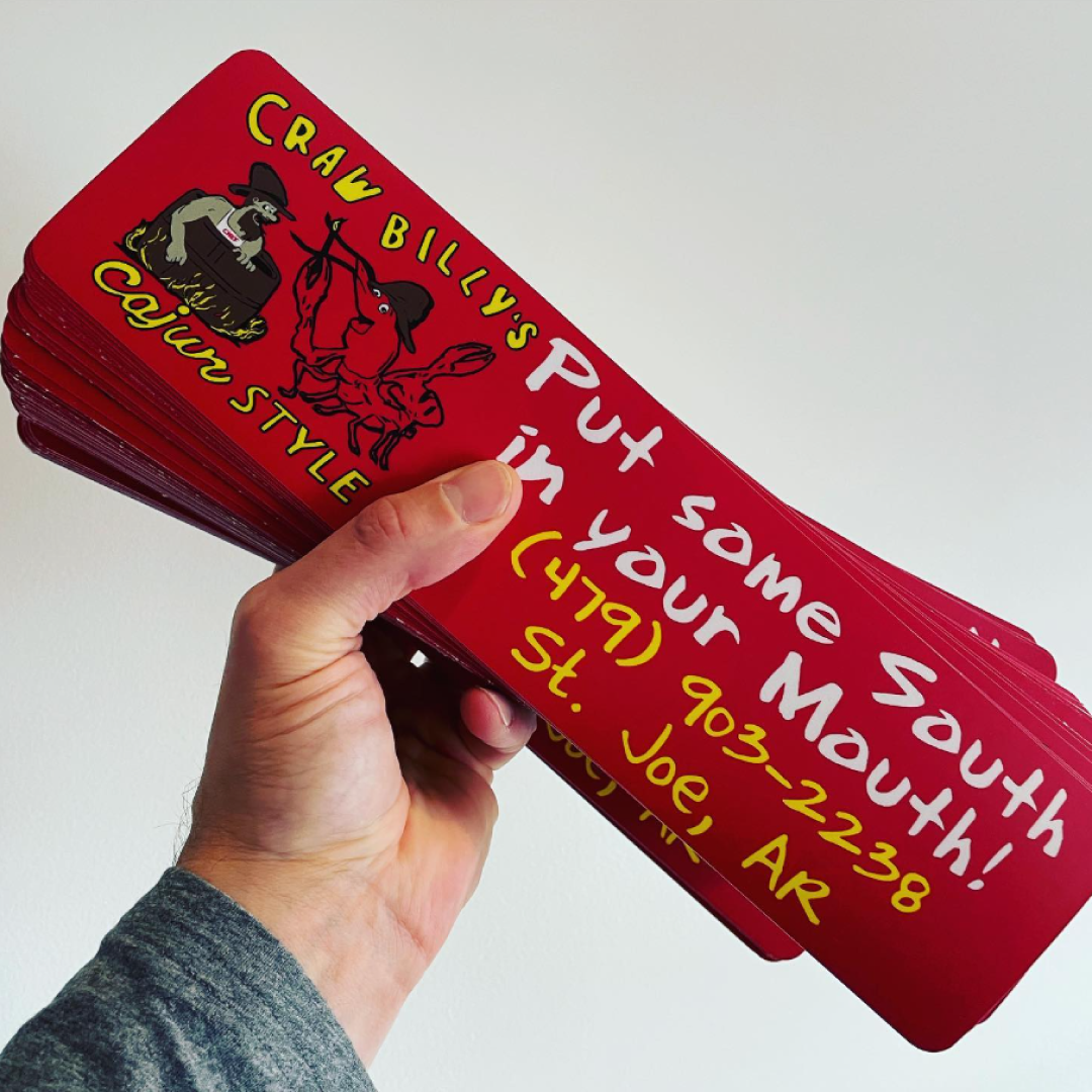 Hand holding a stack of red custom bumper stickers with Craw Billy’s Cajun Style design